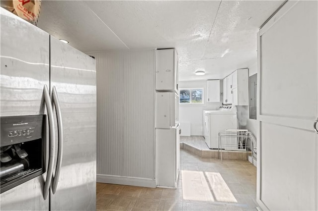 kitchen featuring white refrigerator, stainless steel refrigerator with ice dispenser, white cabinetry, and washer and clothes dryer