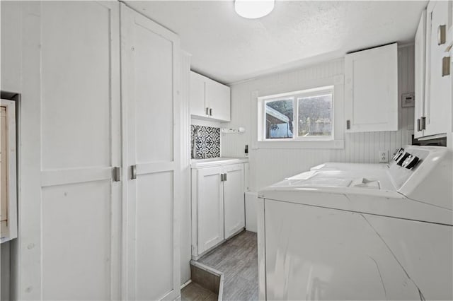 laundry room featuring washing machine and clothes dryer, cabinets, and light hardwood / wood-style floors