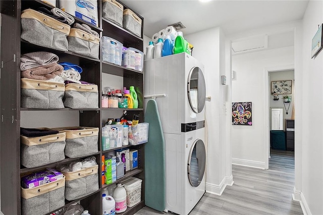 laundry area featuring stacked washer and clothes dryer and wood-type flooring