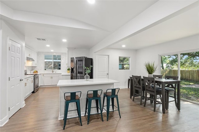 kitchen featuring a breakfast bar, appliances with stainless steel finishes, light hardwood / wood-style floors, white cabinetry, and a kitchen island