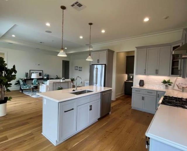 kitchen featuring a kitchen island with sink, stainless steel appliances, sink, gray cabinets, and light wood-type flooring