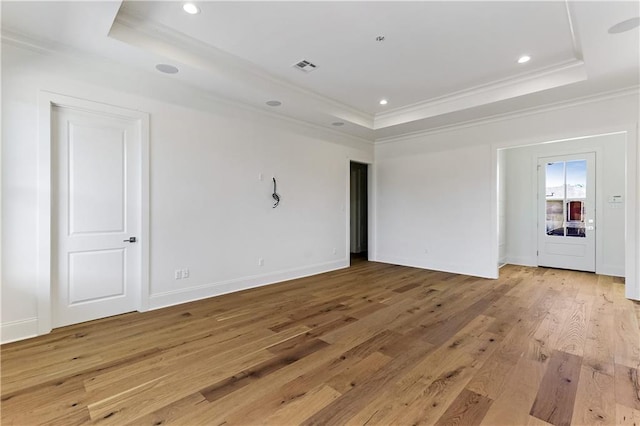 spare room featuring crown molding, a tray ceiling, and light hardwood / wood-style floors