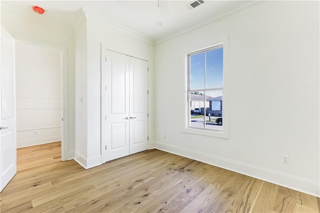 unfurnished bedroom featuring ornamental molding, light hardwood / wood-style flooring, and a closet