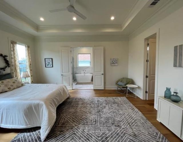 bedroom featuring hardwood / wood-style floors, ensuite bathroom, a tray ceiling, crown molding, and ceiling fan