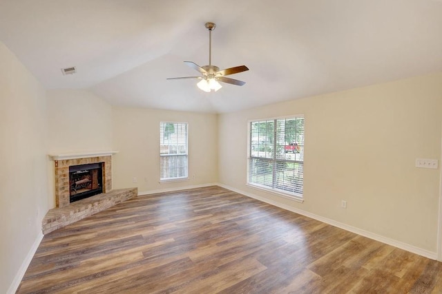 unfurnished living room featuring a brick fireplace, lofted ceiling, ceiling fan, and hardwood / wood-style flooring