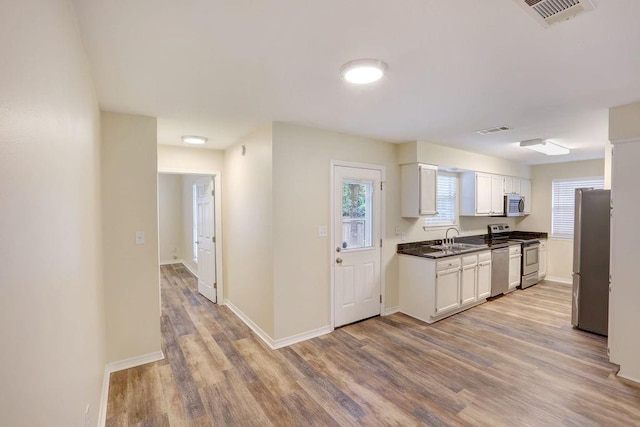 kitchen with light wood-type flooring, appliances with stainless steel finishes, sink, and white cabinets