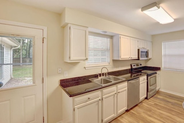 kitchen with white cabinets, light wood-type flooring, stainless steel appliances, and sink