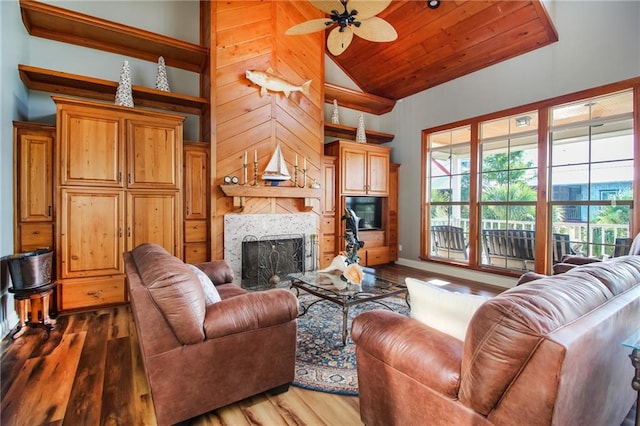 living room with high vaulted ceiling, a tile fireplace, ceiling fan, wood-type flooring, and wood walls