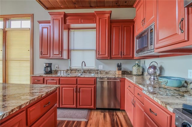 kitchen with appliances with stainless steel finishes, light hardwood / wood-style flooring, sink, and light stone countertops