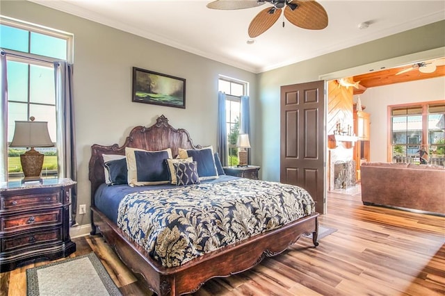 bedroom with ceiling fan, multiple windows, and hardwood / wood-style flooring