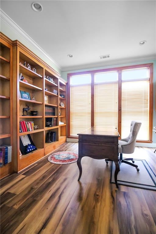 home office with built in shelves, ornamental molding, and hardwood / wood-style floors