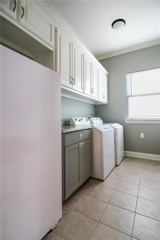 laundry room with light tile patterned floors, washing machine and dryer, cabinets, and ornamental molding