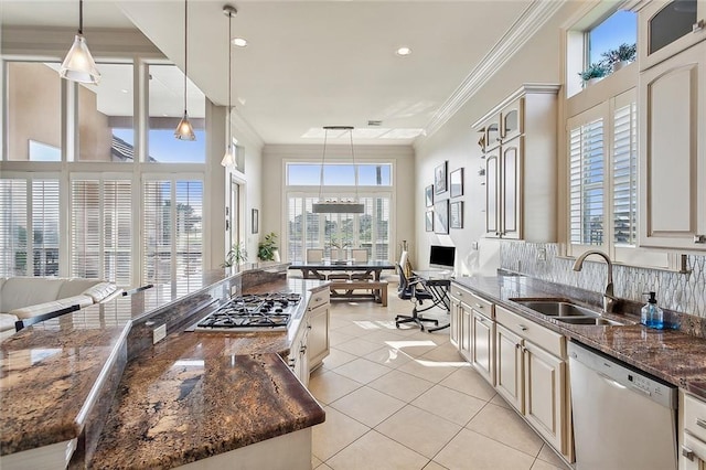 kitchen featuring dark stone countertops, dishwasher, sink, tasteful backsplash, and decorative light fixtures