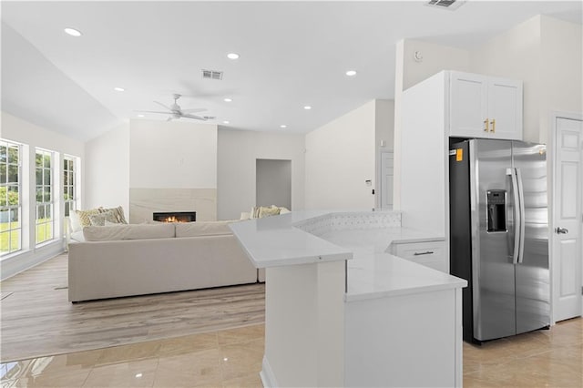 kitchen featuring lofted ceiling, stainless steel refrigerator with ice dispenser, light tile patterned floors, ceiling fan, and white cabinetry