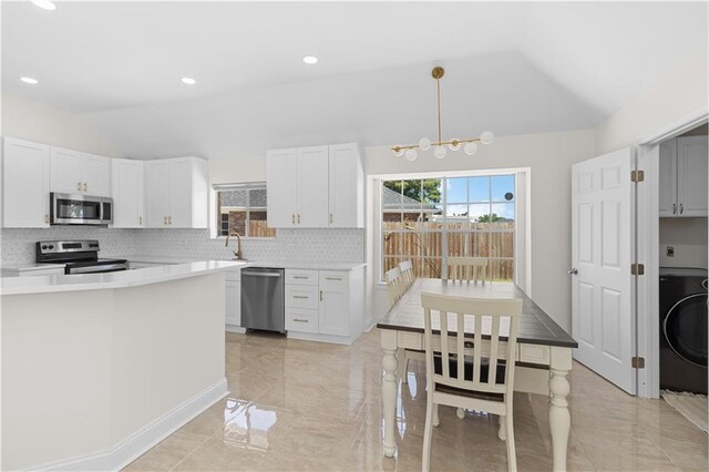 kitchen with lofted ceiling, stainless steel appliances, backsplash, washer / dryer, and light tile patterned floors