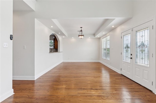 foyer entrance with an inviting chandelier, hardwood / wood-style floors, a tray ceiling, and sink