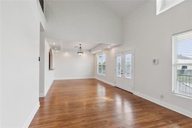 unfurnished living room with a towering ceiling and dark hardwood / wood-style flooring