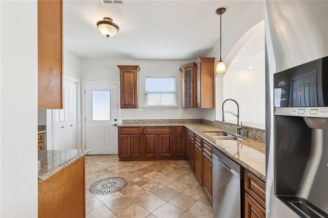 kitchen featuring sink, light stone counters, decorative light fixtures, light tile patterned floors, and appliances with stainless steel finishes