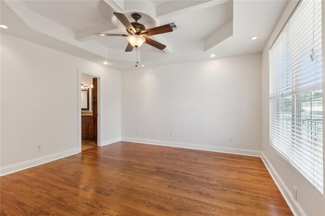 spare room with hardwood / wood-style flooring, a raised ceiling, and ceiling fan