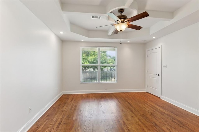 empty room featuring ceiling fan, a tray ceiling, and hardwood / wood-style floors