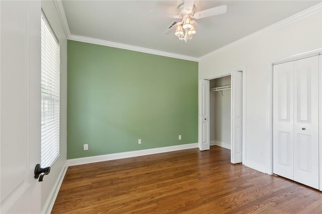 unfurnished bedroom featuring ornamental molding, dark wood-type flooring, two closets, and ceiling fan