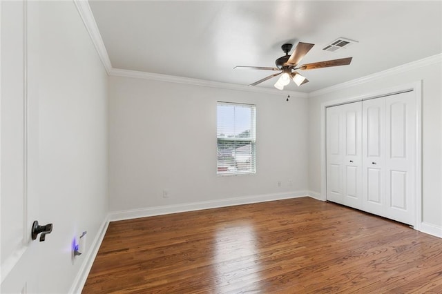 unfurnished bedroom with dark wood-type flooring, ornamental molding, a closet, and ceiling fan