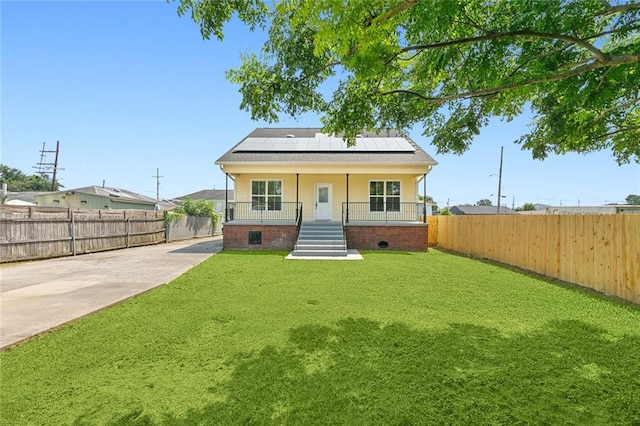 view of front of property with a porch, a front lawn, and solar panels