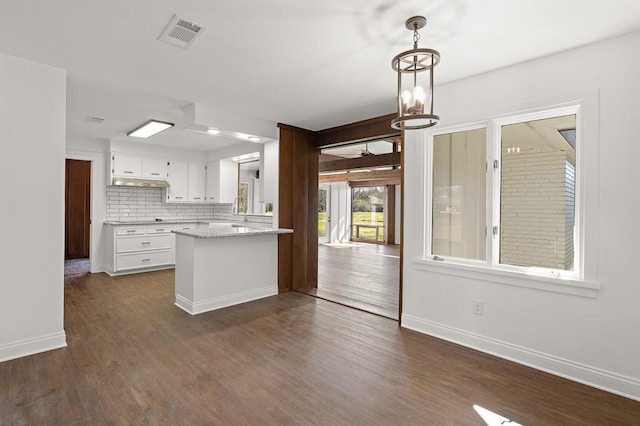 kitchen with tasteful backsplash, white cabinets, dark wood-type flooring, and a notable chandelier