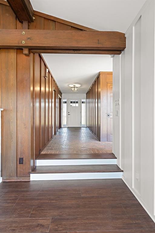 hallway with dark hardwood / wood-style flooring, vaulted ceiling, and wood walls