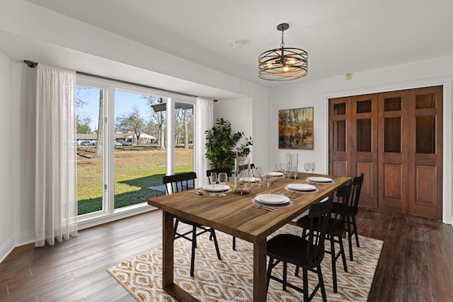 dining space with dark wood-type flooring and an inviting chandelier