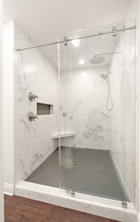 bathroom with hardwood / wood-style flooring and tiled shower