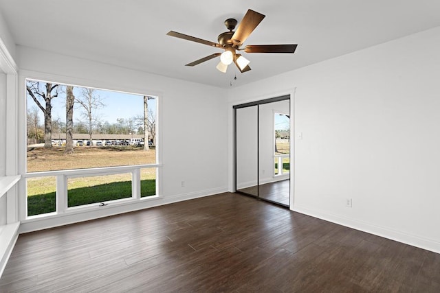 spare room featuring ceiling fan, dark hardwood / wood-style flooring, and a wealth of natural light