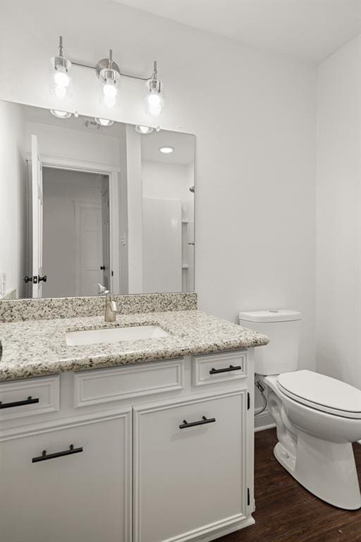 bathroom featuring wood-type flooring, vanity, and toilet