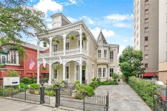 view of front of home with a fenced front yard, covered porch, and a balcony