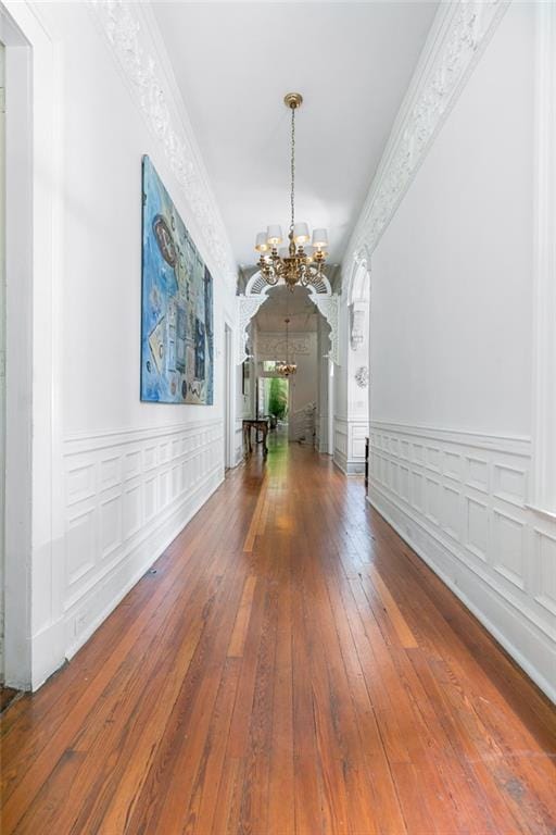 interior space with a wainscoted wall, ornamental molding, hardwood / wood-style flooring, a decorative wall, and a chandelier