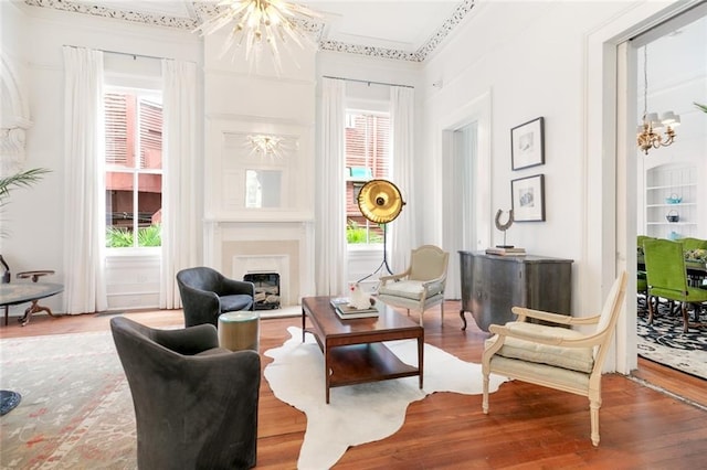 living area with wood finished floors, plenty of natural light, a chandelier, and a fireplace