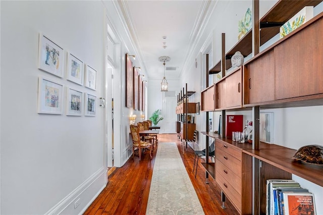 hall with baseboards, dark wood finished floors, and crown molding