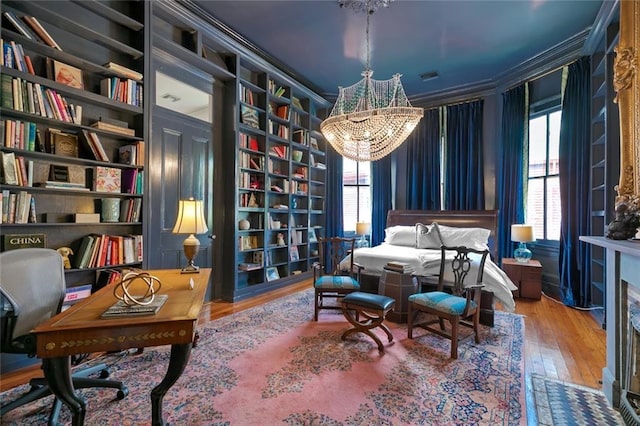 living area featuring visible vents, built in shelves, wood-type flooring, an inviting chandelier, and crown molding