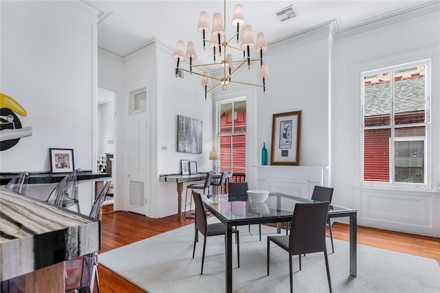 dining area featuring a notable chandelier, visible vents, ornamental molding, and wood finished floors