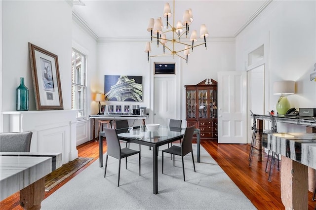 dining space with wood finished floors, an inviting chandelier, and ornamental molding