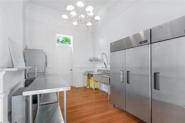 kitchen featuring an inviting chandelier, crown molding, and light wood-style flooring