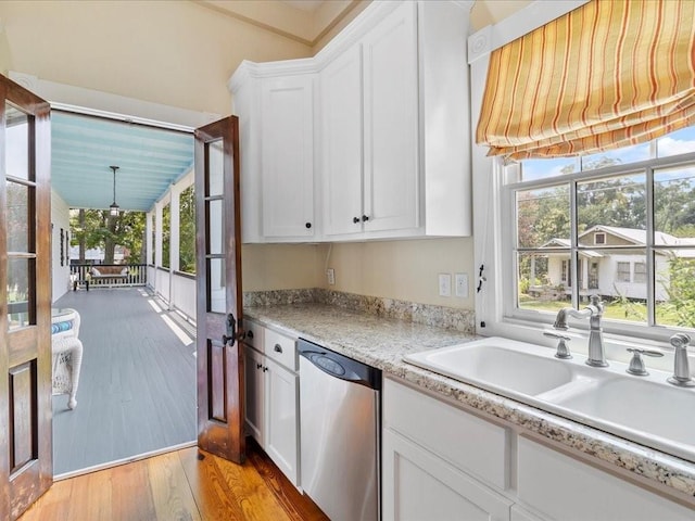 kitchen featuring sink, stainless steel dishwasher, plenty of natural light, light hardwood / wood-style floors, and white cabinets