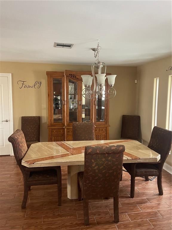 dining area featuring dark wood-type flooring and an inviting chandelier