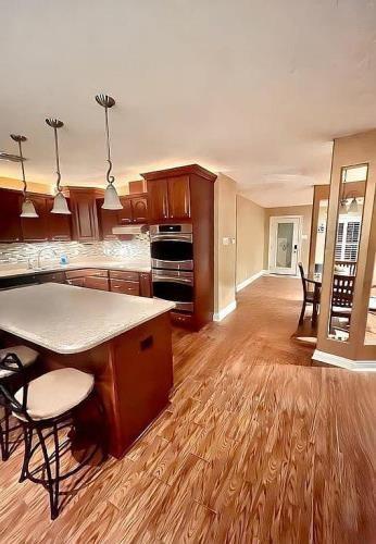 kitchen featuring a kitchen breakfast bar, wood-type flooring, hanging light fixtures, decorative backsplash, and double oven