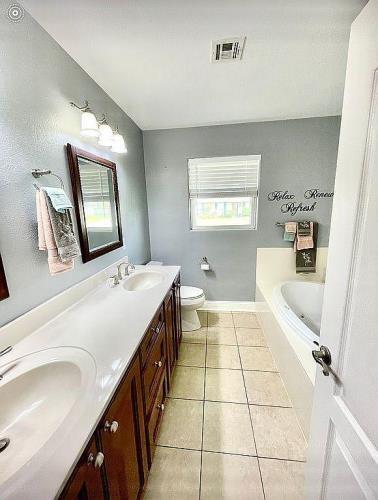 bathroom with tiled tub, vanity, toilet, and tile patterned flooring