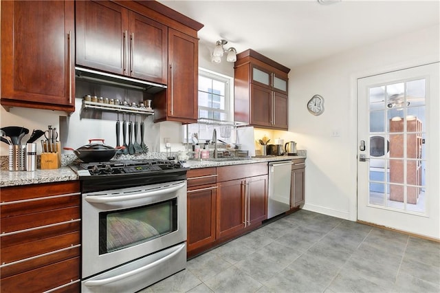 kitchen with stainless steel appliances, light stone countertops, and sink