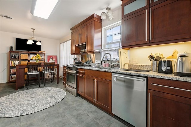 kitchen with pendant lighting, sink, light stone counters, and appliances with stainless steel finishes