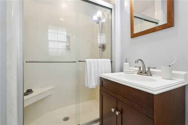 bathroom featuring a shower with door and vanity