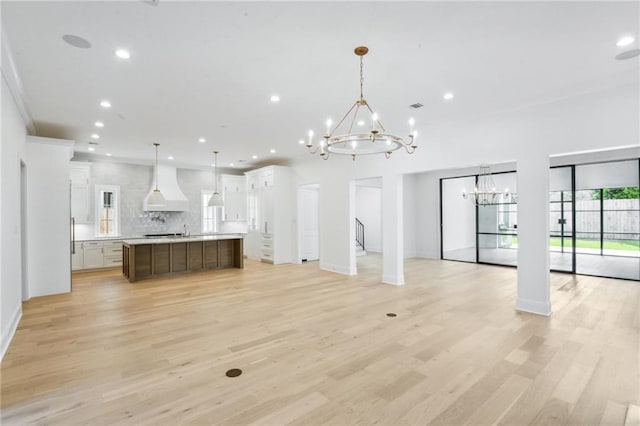 unfurnished living room featuring a notable chandelier and light hardwood / wood-style floors