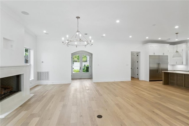 unfurnished living room with french doors, crown molding, a chandelier, and light hardwood / wood-style floors